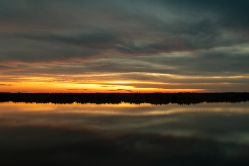 body of water under cloudy sky during sunset