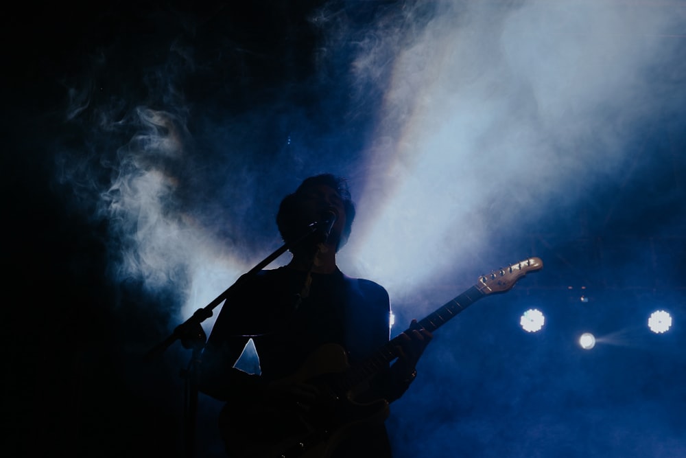 woman in black tank top playing guitar