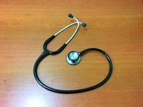 Close-up of a stethoscope resting on a light wooden table.