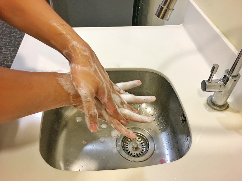 person washing hands on sink