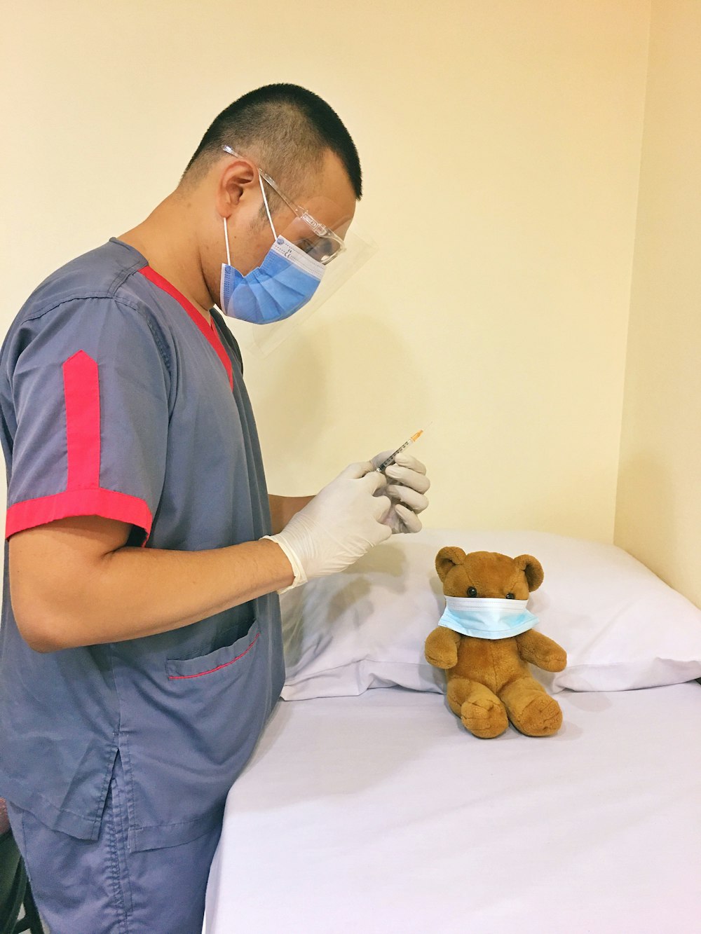 man in blue and red polo shirt holding a pen and a brown bear plush toy