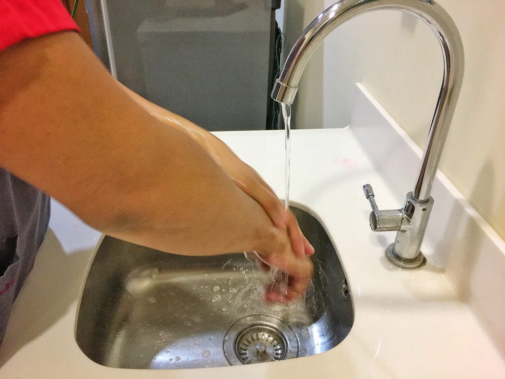 person washing hand on sink