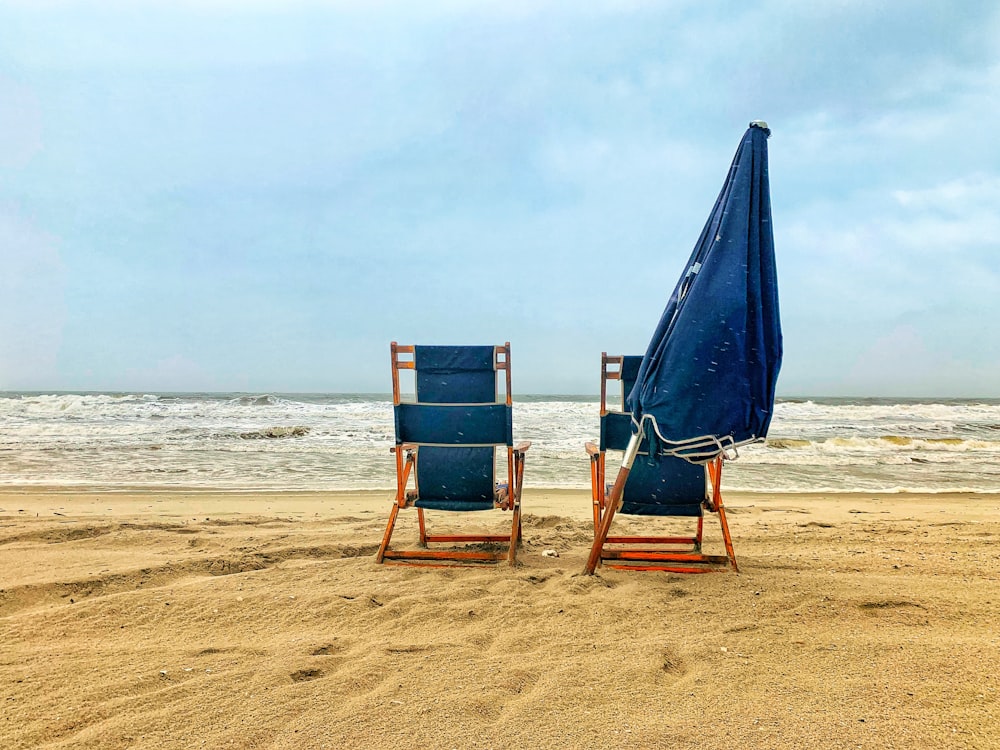 낮 동안 해변에 파란색과 갈색 나무 의자