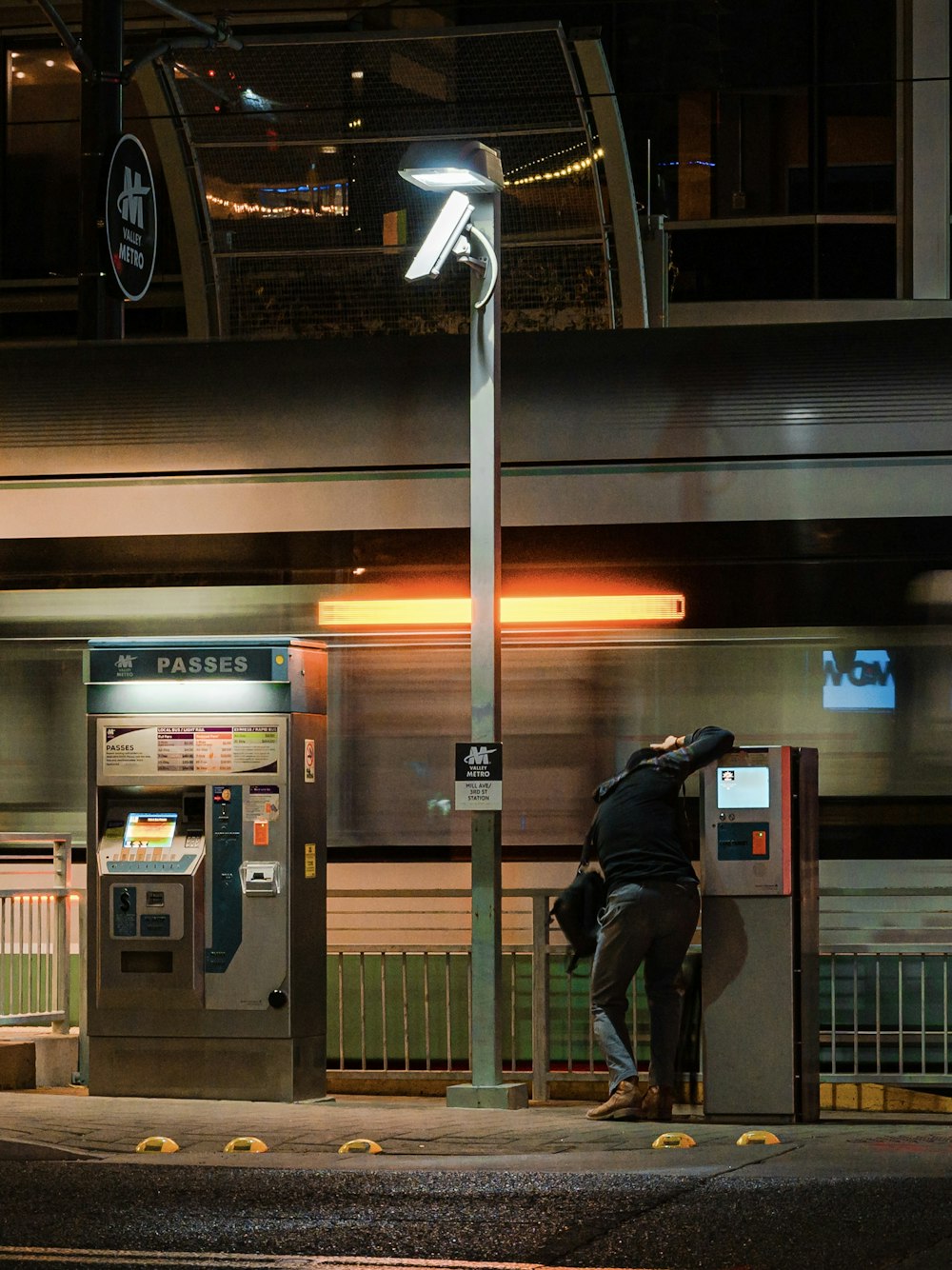 man in black jacket and gray pants standing beside gray telephone booth