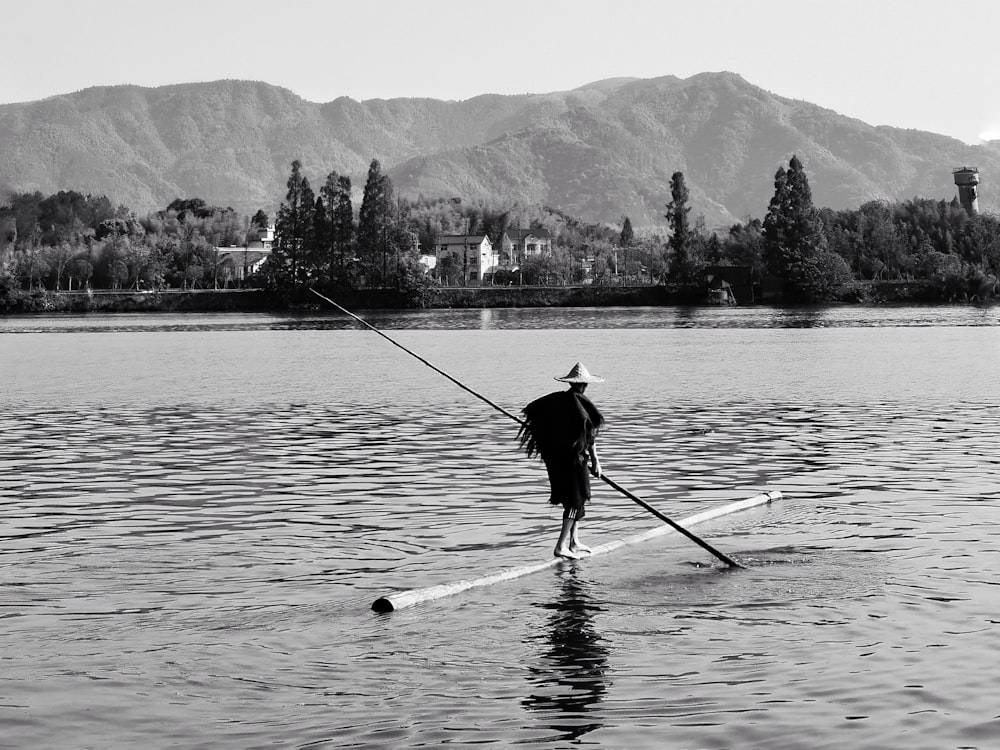 man in black jacket and pants fishing on lake during daytime