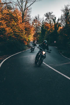 Bikers riding off-road trails surrounded by autumn-colored forests near Saluzzo.