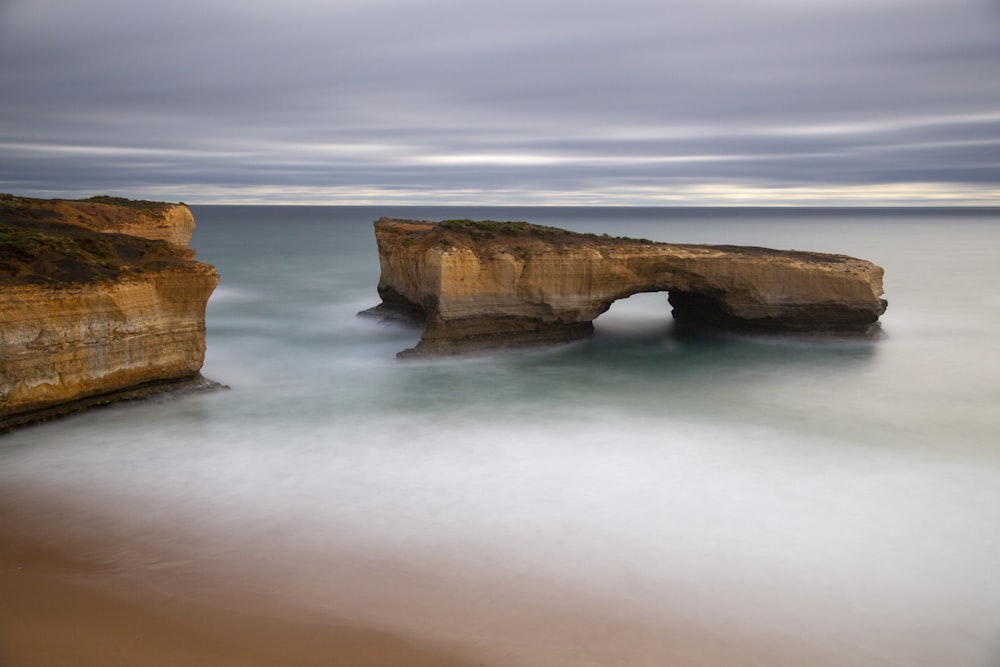 brown rock formation on body of water during daytime