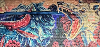 A vibrant mural depicting a surreal scene with a large whale underwater, icebergs and mountains in the background, and a menacing wolf-like creature with an open mouth surrounded by red flowers. A sign on the wall reads 'Private Property No Trespassing' in both English and Spanish.