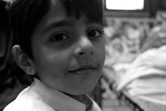 A candid portrait of a Ukrainian child smiling softly amidst a backdrop of a quiet village street.