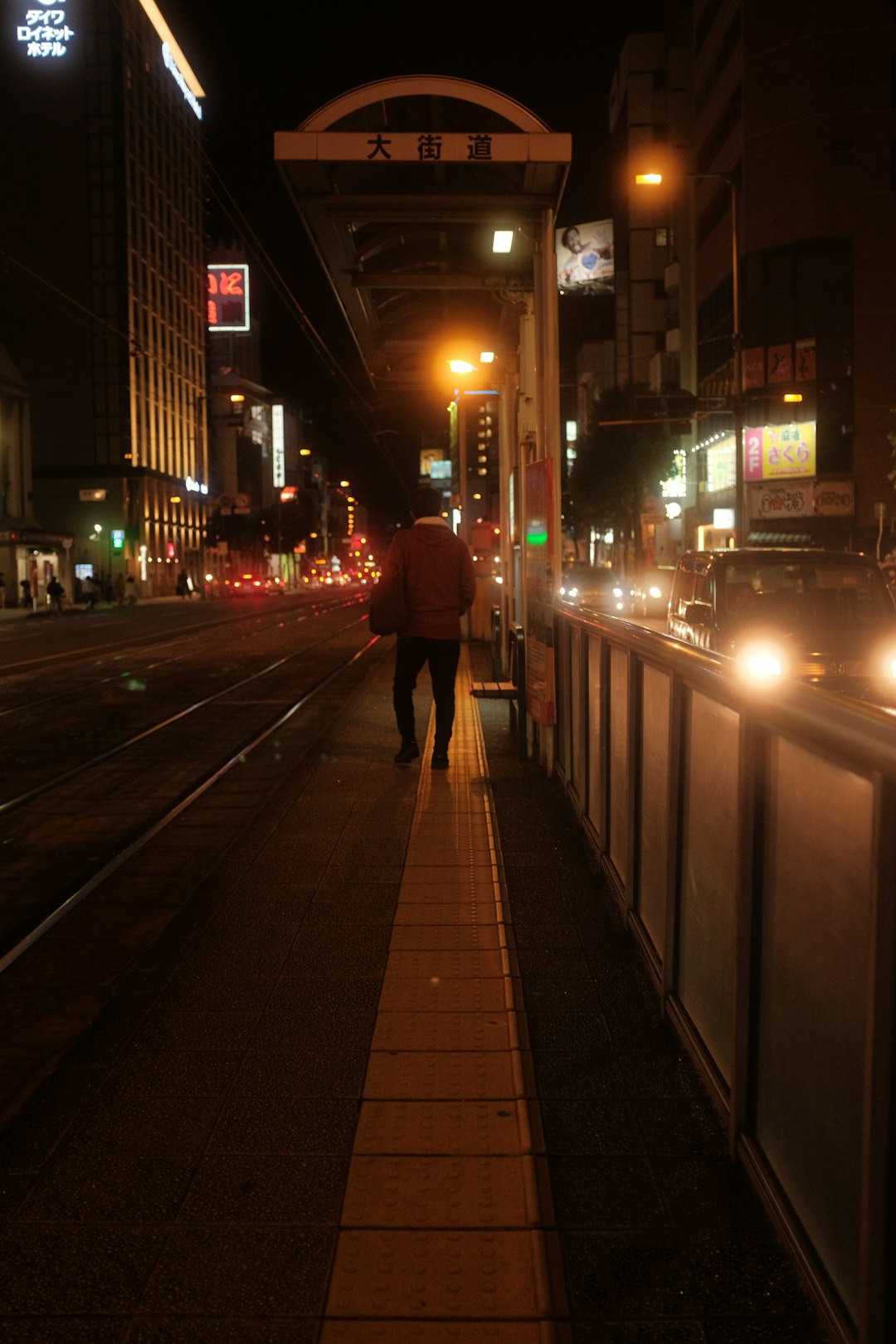 person in red jacket walking on sidewalk during night time