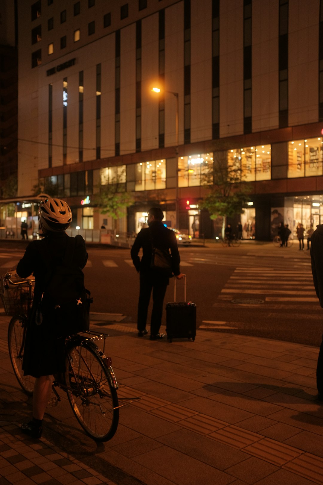 man in black jacket and black pants standing beside bicycle during night time