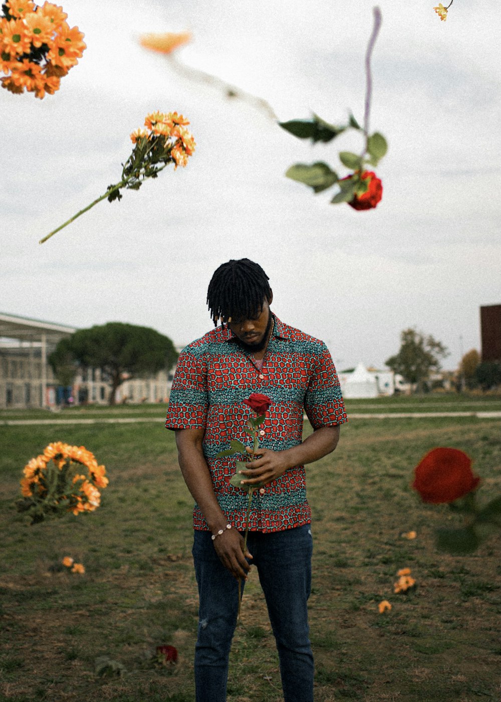 man in red and white checkered button up shirt and blue denim jeans standing on flower