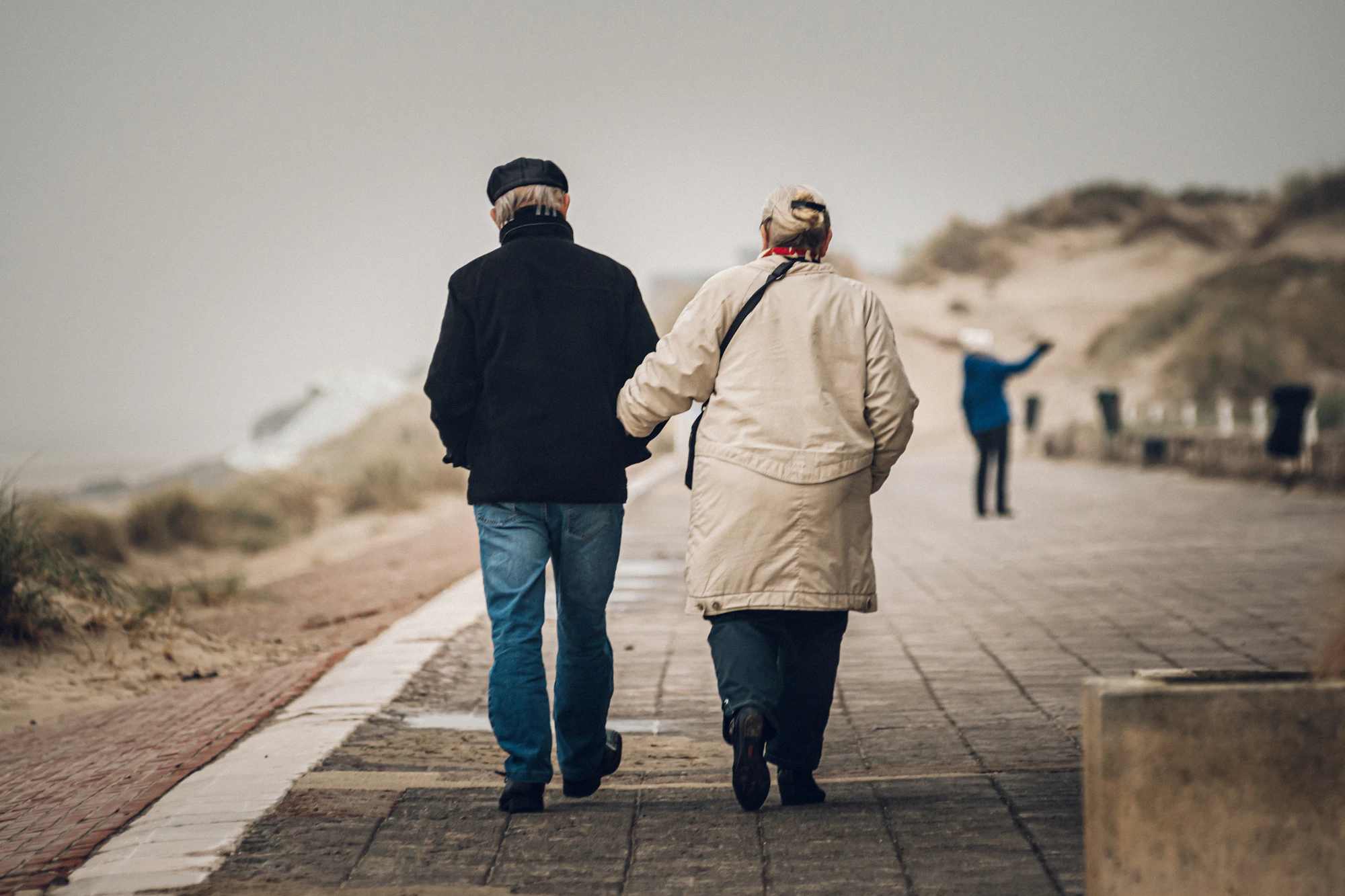 A couple walking a windswept shore path