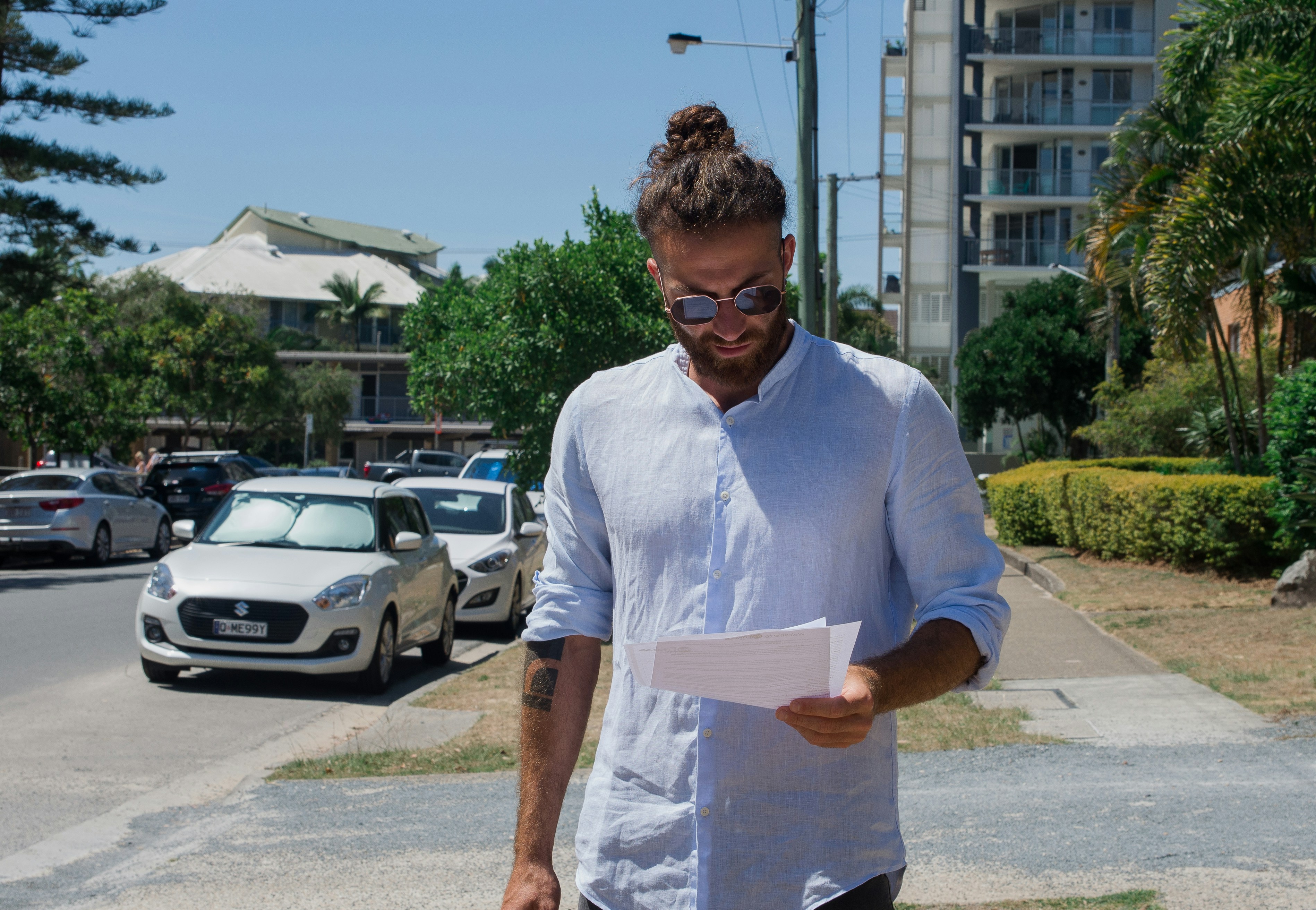 totaled vehicle insurance claim paperwork - man in white button up t-shirt holding white printer paper