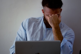 man in blue dress shirt holding silver macbook