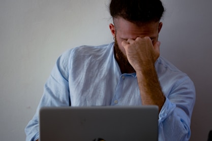 man in blue dress shirt holding silver macbook
