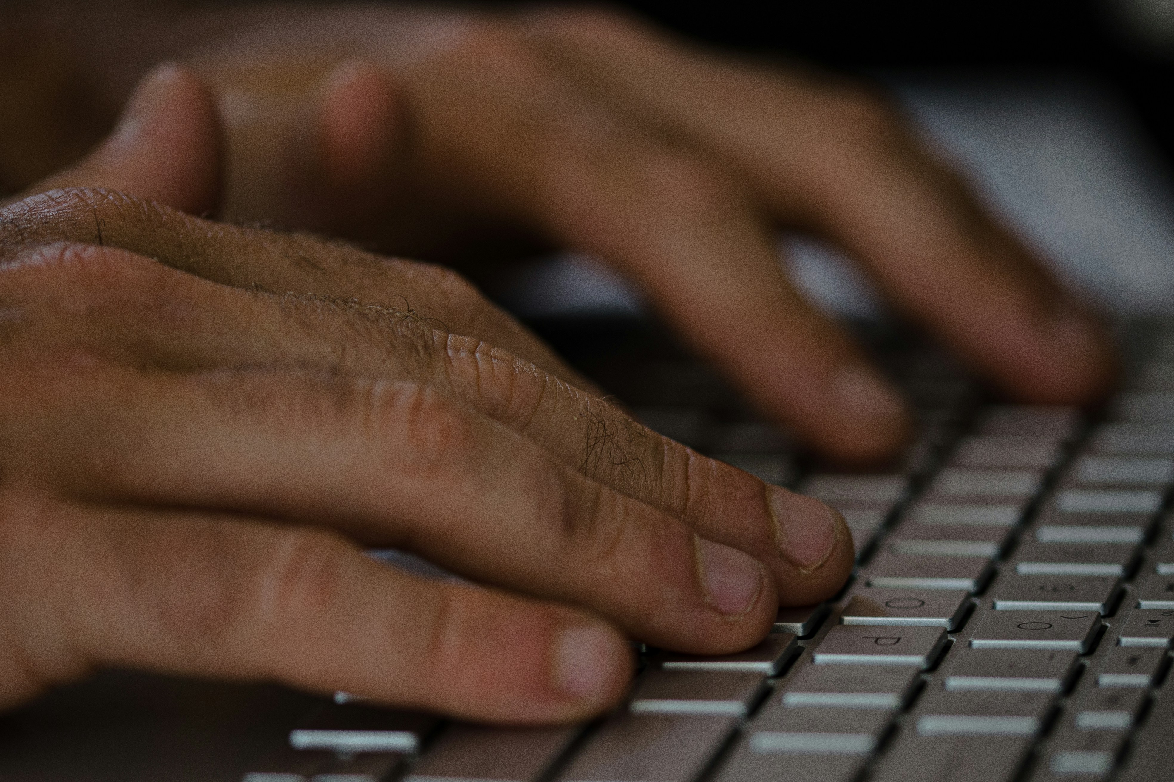 Close-up of hands typing on keyboard with SEO analytics on screen.