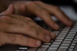 Close-up of hands typing on a keyboard with digital icons floating around.