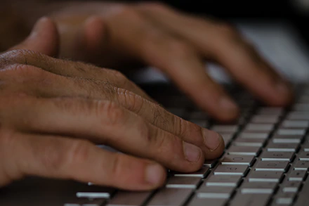 Close-up of hands typing on a keyboard with digital data overlays in the background.
