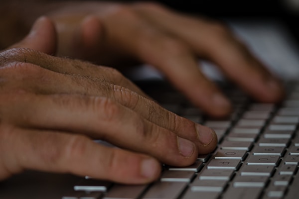 Close-up of hands typing on a keyboard with medical charts nearby.