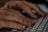 Close-up view of hands typing on a computer keyboard. The fingers are poised over the keys, suggesting active engagement with typing or data entry.