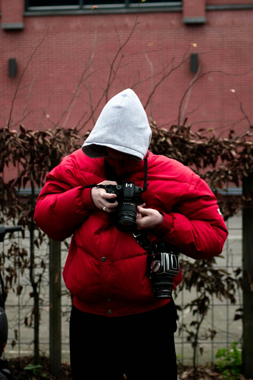 man in red jacket holding black dslr camera