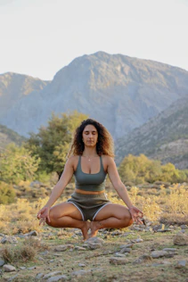 A peaceful scene of a woman meditating outdoors at sunrise, surrounded by nature.