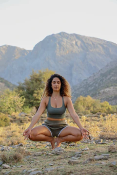 A calm person sitting cross-legged in meditation surrounded by nature.