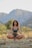 A serene person meditating outdoors surrounded by nature.