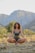A serene person meditating outdoors surrounded by nature.