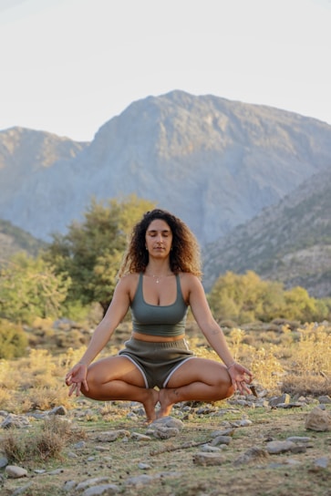 A person meditating outdoors surrounded by nature during sunrise.