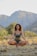 A serene person meditating in a tranquil outdoor setting, surrounded by nature.