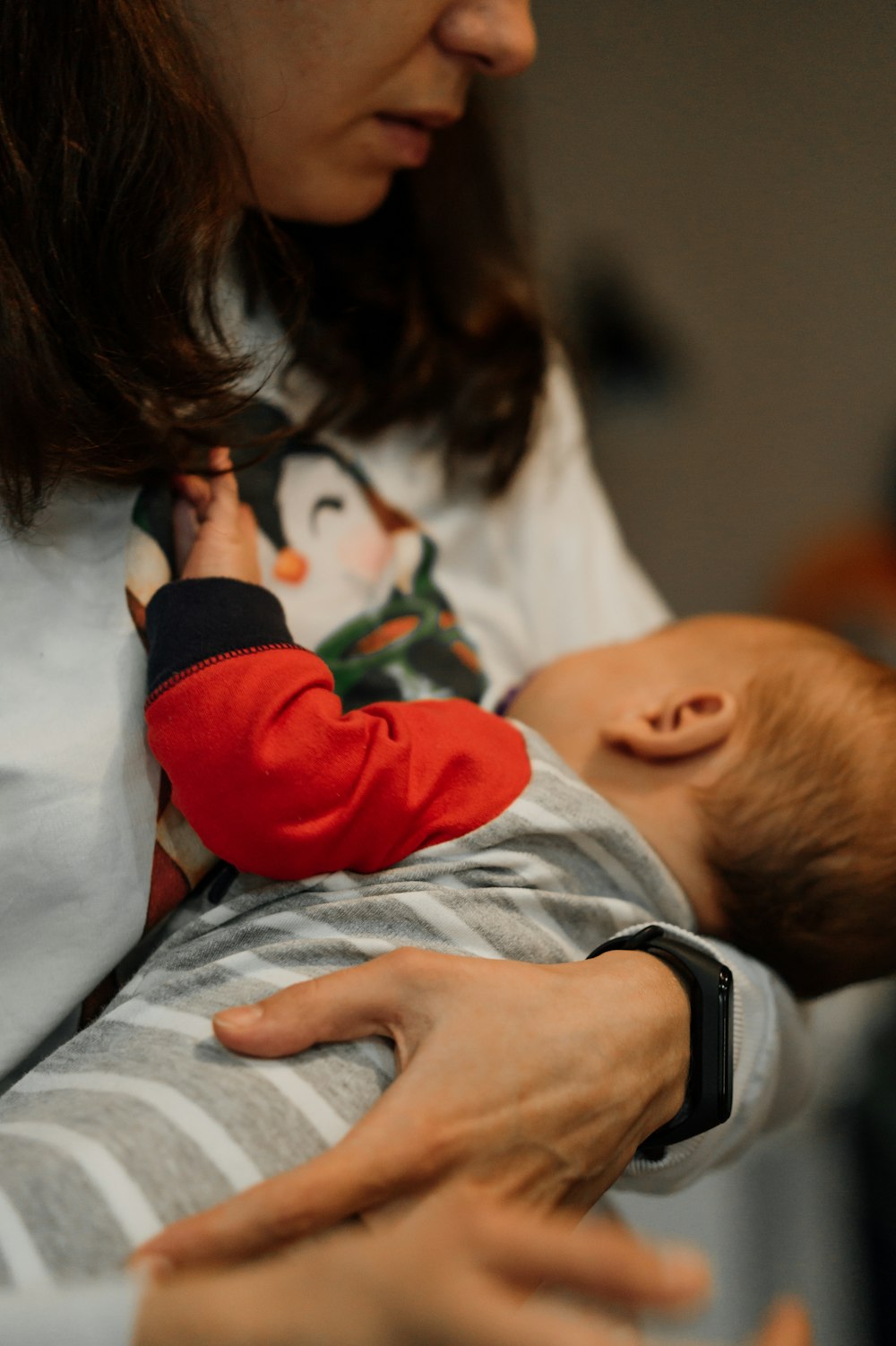 Frau in weißem Langarmshirt mit Baby in rot-weißem Langarmshirt