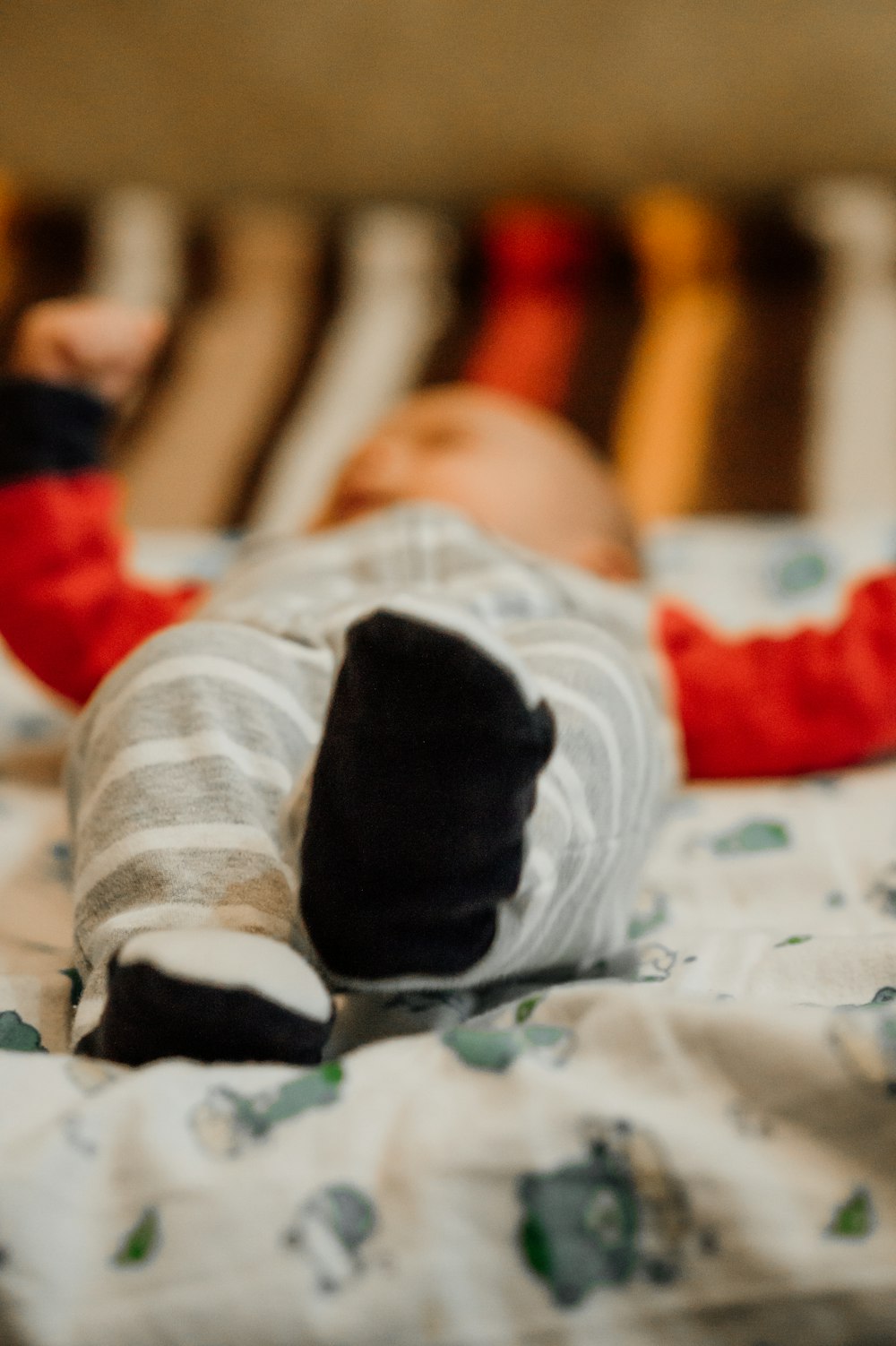 baby in white and black socks lying on bed