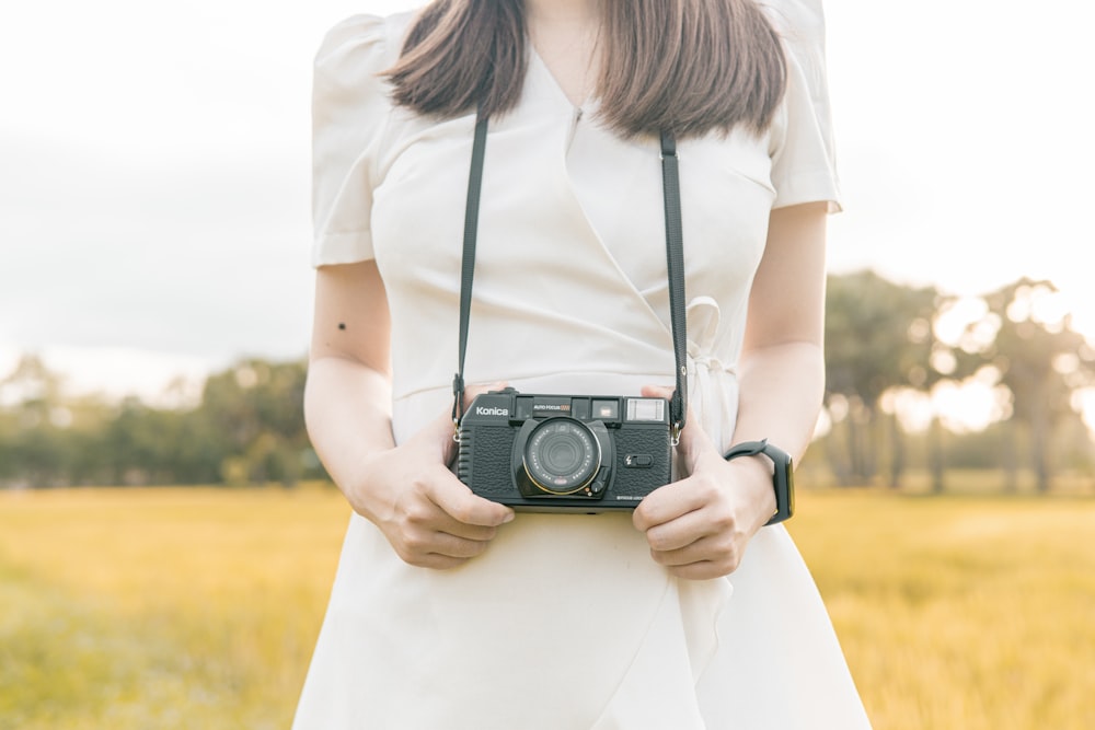 woman in white shirt holding black and silver dslr camera