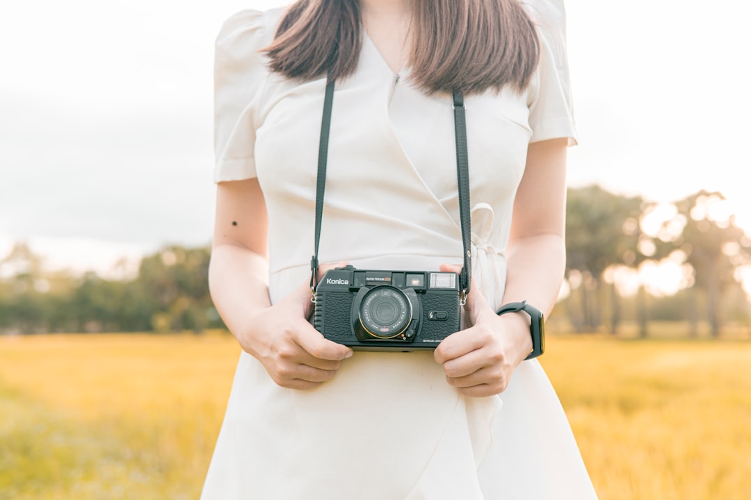 woman in white shirt holding black and silver dslr camera