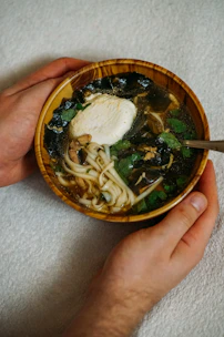 A hand holding a spoonful of nourishing bird’s nest soup, showcasing its rich, silky consistency.