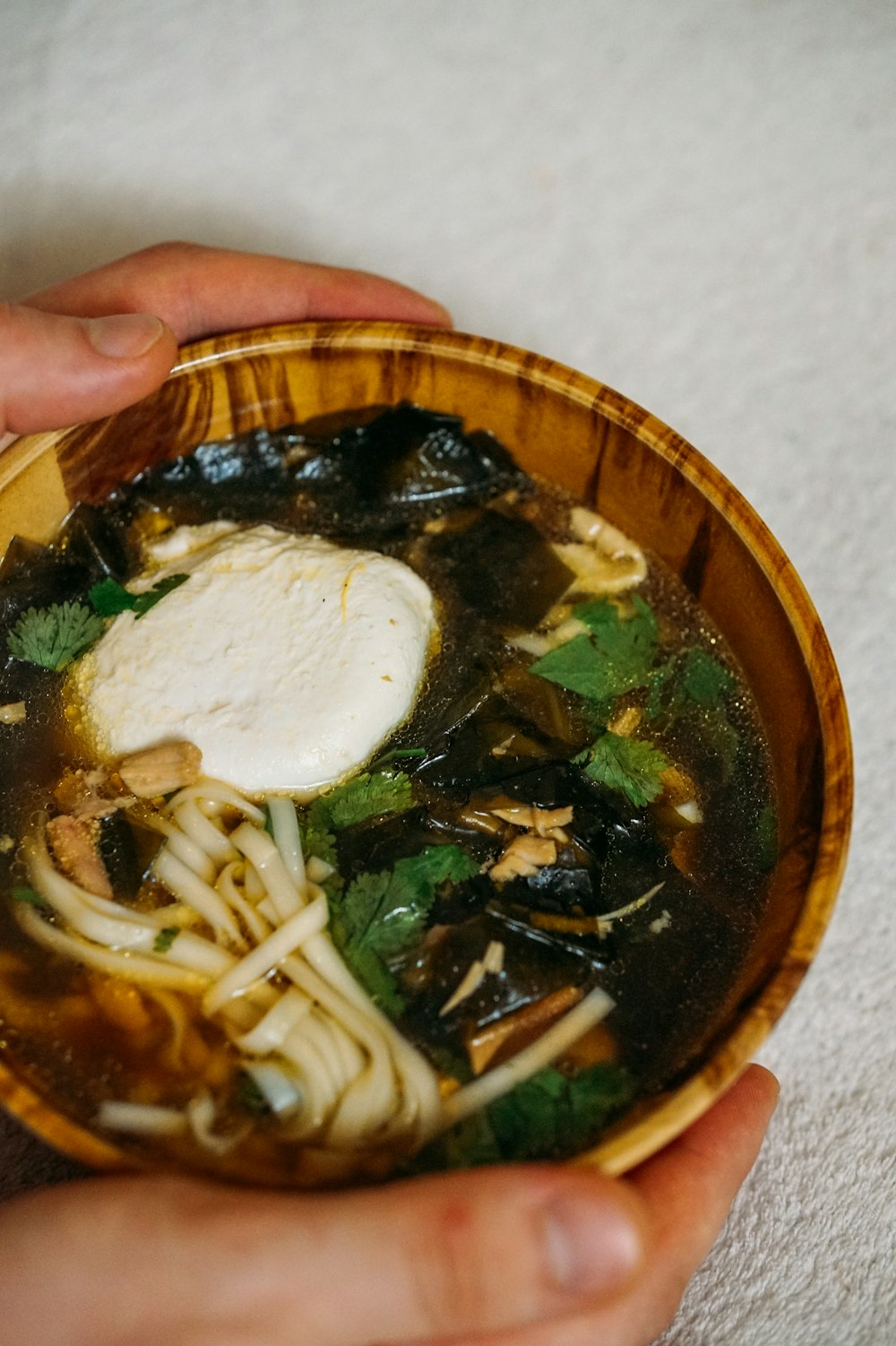 person holding brown ceramic bowl with soup