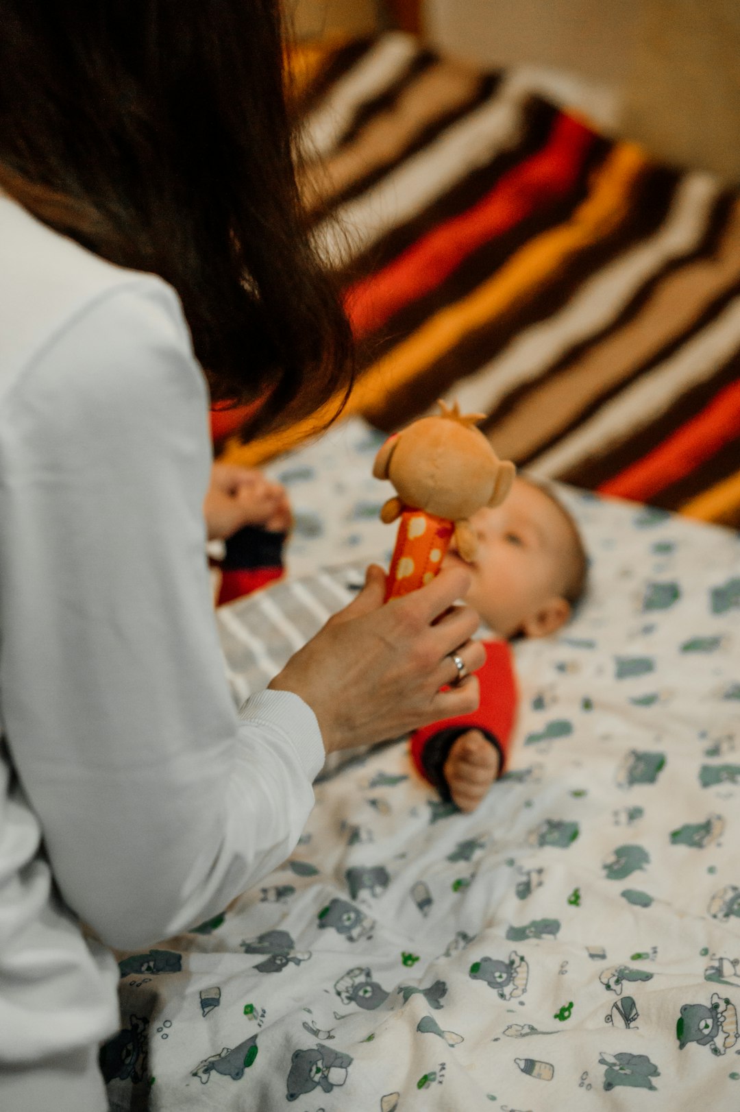 girl in white long sleeve shirt holding brown bear plush toy