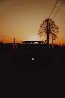 A stunning sunset with a sports car silhouette in the foreground.