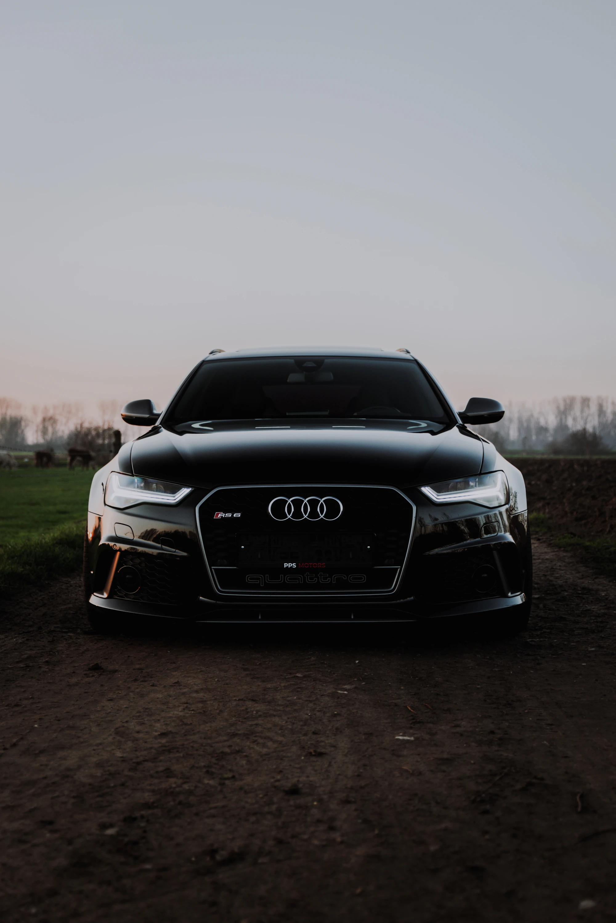 Black sedan facing forward on an open road in dawn haze