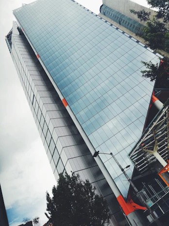 Glass skyscraper exterior with a subtle orange tint under a clear blue sky, symbolizing growth and stability.