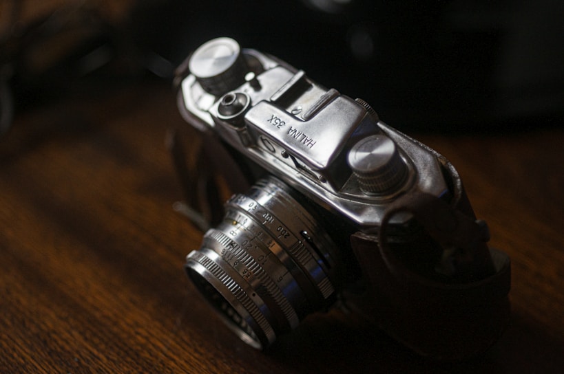 A close-up shot of a vintage camera resting on a wooden table, capturing a nostalgic vibe.