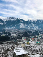 aerial view of city near snow covered mountains during daytime