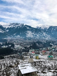aerial view of city near snow covered mountains during daytime
