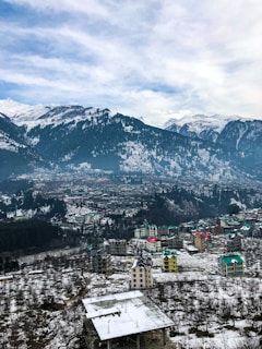 aerial view of old manali city near snow covered mountains during daytime