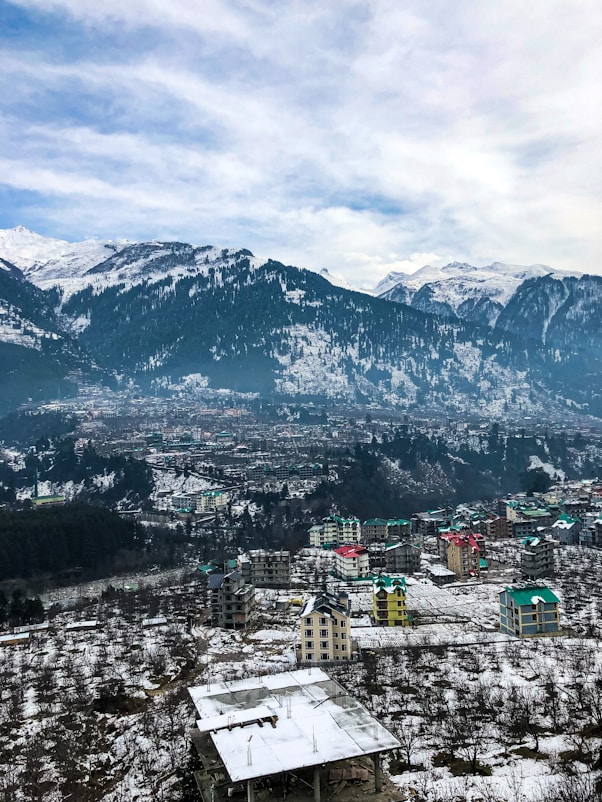 aerial view of old manali city near snow covered mountains during daytime