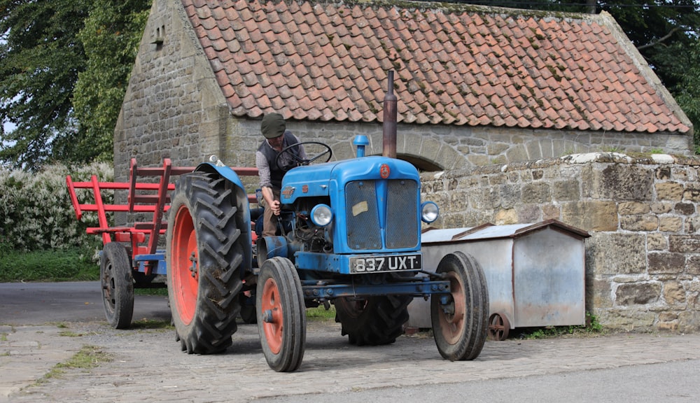 blue tractor parked beside brick wall