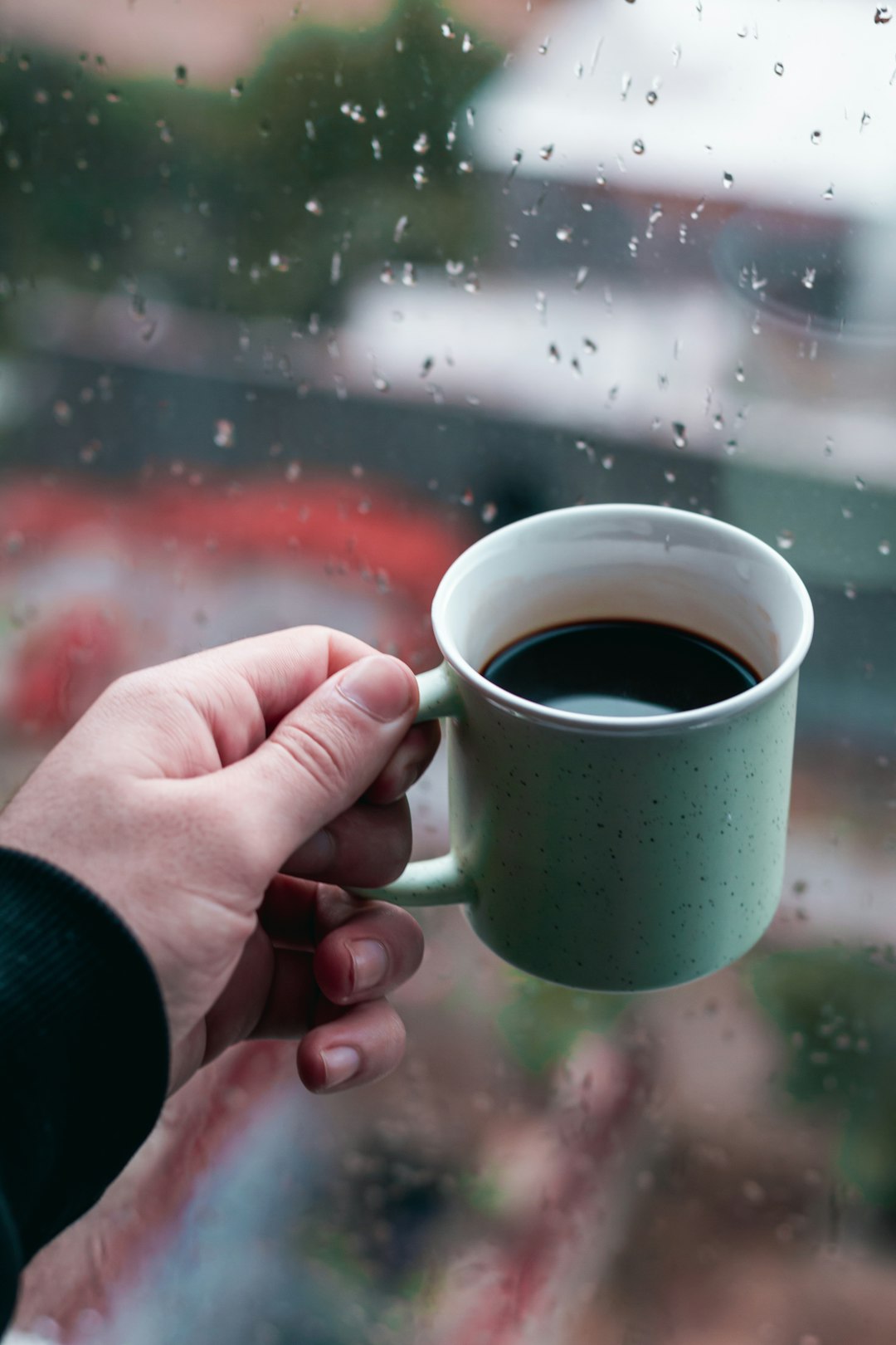 person holding green ceramic mug with brown liquid