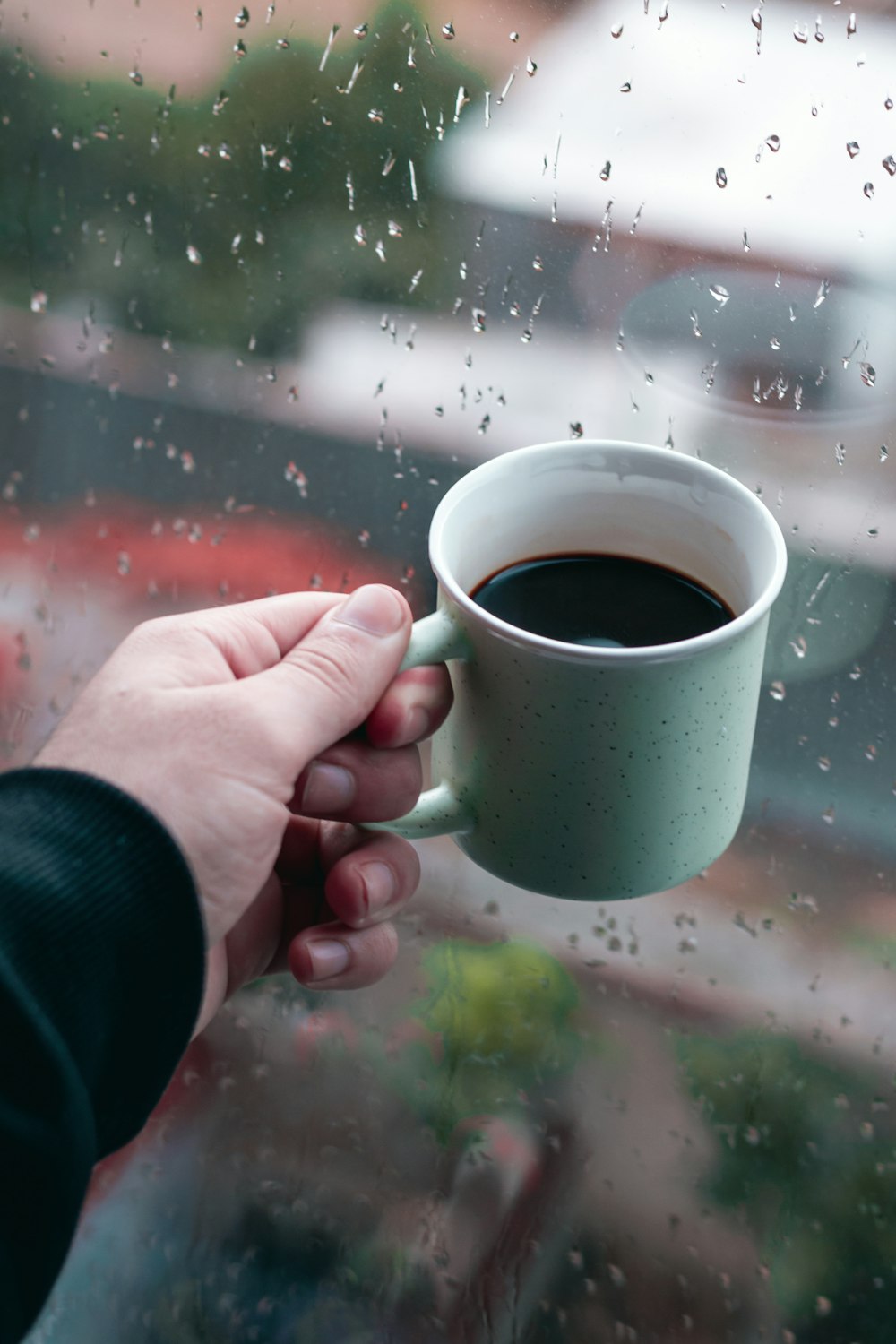 personne tenant une tasse en céramique verte avec du café